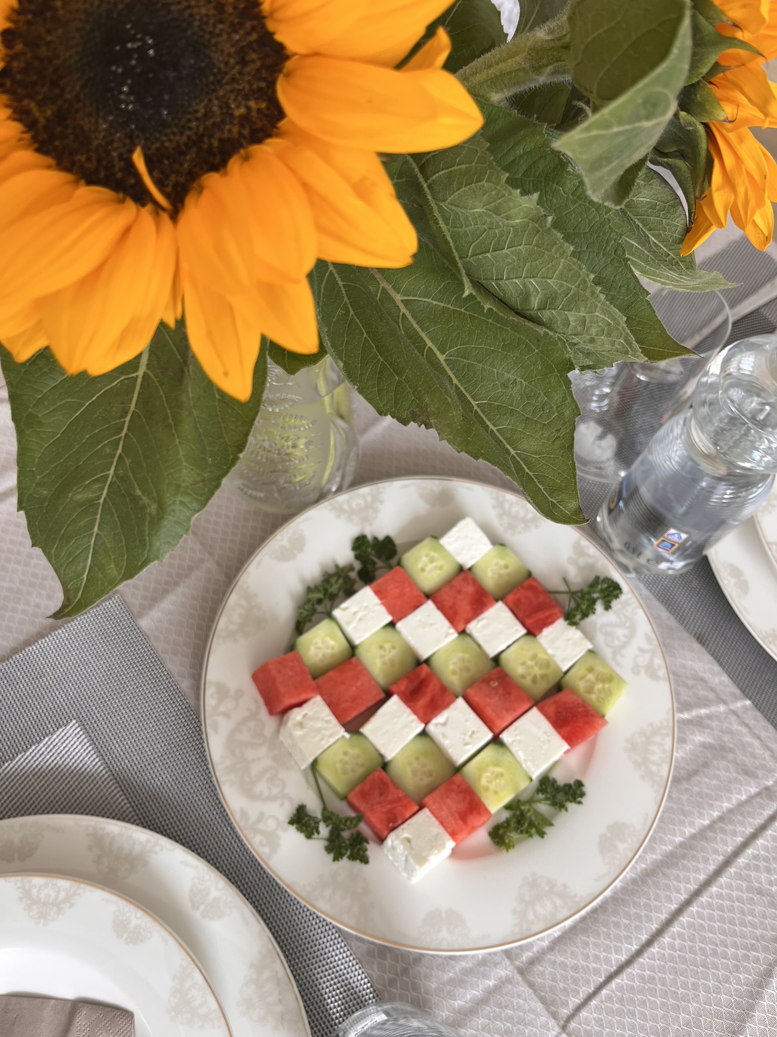 Sommertisch mit Sonnenblumen, Wassermelone, Gurke und Käse