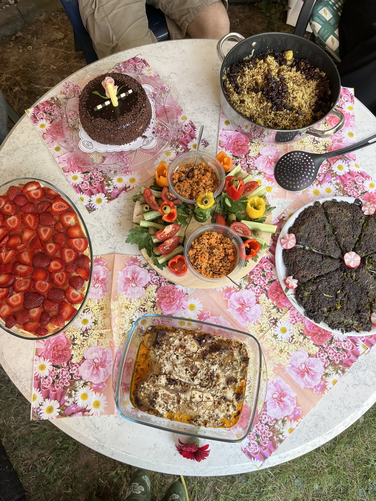 Gartentisch mit persischen Speisen, Erdbeeren und Blumen